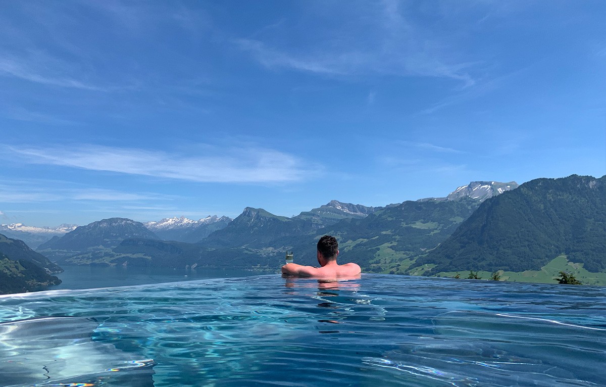 Nick in an infinity pool overlooking a lake and mountains